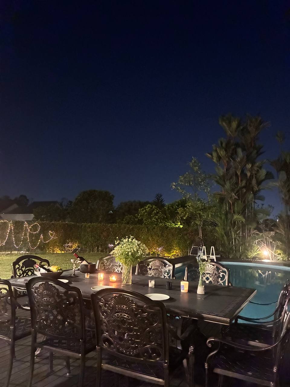 Poolside dinner setup with fairy lights and candles